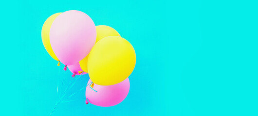 Bunch of festive colorful yellow pink balloons on a blue background
