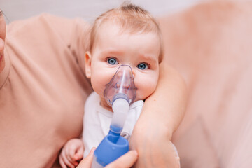 A little girl inhales from an inhaler with a nebulizer at home. A child with a viral disease in an...