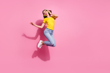 Fototapeta na wymiar Photo of pretty charming lady dressed yellow clothes smiling enjoying songs earphones jumping high empty space isolated pink color background