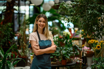 Florist working in flower shop while smiling and looking at a camera