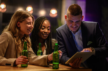 Cheerful colleagues drinking beer in the bar together after work