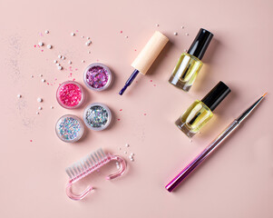 A set of sequins, varnishes, brushes for creating a festive manicure on a pink background. Copy space