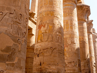 Stone columns with Egyptian hieroglyphs and ancient drawings in the Karnak temple. Close-up. Luxor, Egypt.