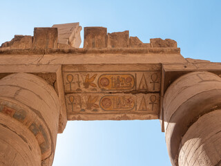 Egyptian hieroglyphs and ancient drawings in the Karnak Temple at the top of the column. Close-up. Luxor, Egypt.