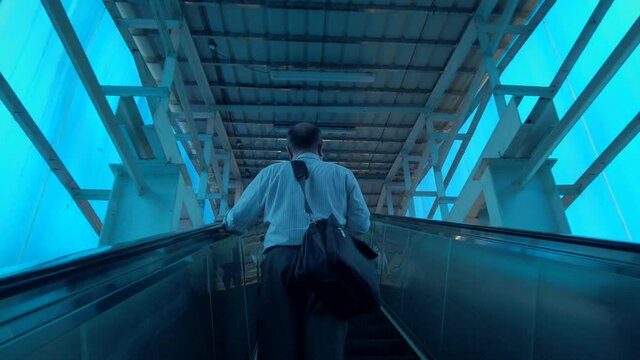 old blind man with black massganger bag using escaletor blue shade india mira road station railway suspisues .