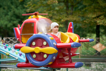 Little girl rides a carousel airplane