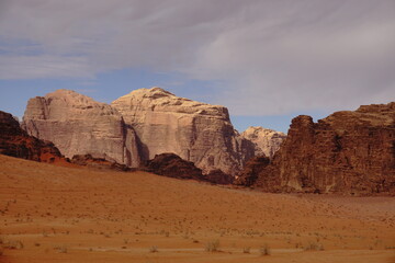 Fototapeta na wymiar red relief weathered mountains in the Wadi Rum desert, dry bushes grow in a sandy valley, Jordan