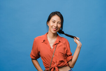 Young Asia lady with positive expression, smile broadly, dressed in casual clothing and looking at camera over blue background. Happy adorable glad woman rejoices success. Facial expression concept.