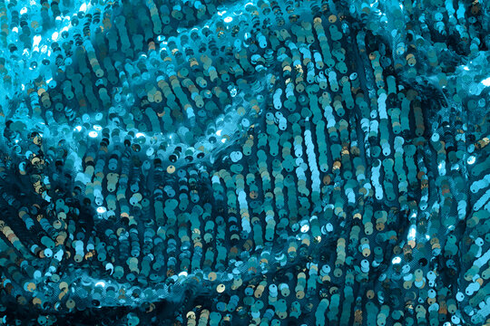 Shiny and glittering turquoise blue fabric with sequins. Abstract background. Events, celebrations, Christmas, New Year. Trendy backdrop.