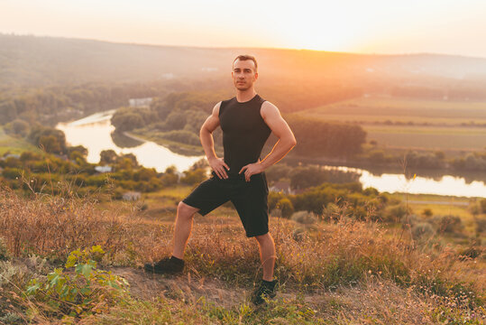 A nice photo of a man with muscles on a hill looking at the camera .
