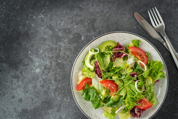 Fresh vegetarian salad on dark stone background. Top view, copy space.