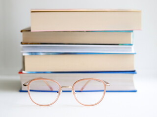 Stack of books and glasses on table, on white background.