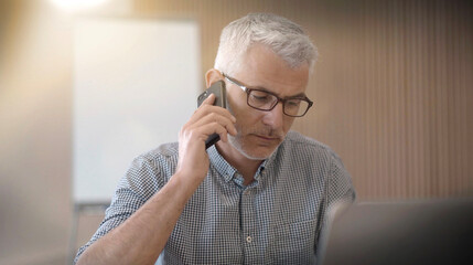 40 year old man with glasses on the phone in an office