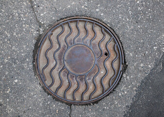  Old iron manhole cover on the city street.