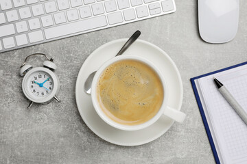 Cup of drink, alarm clock and stationery on light grey table, flat lay. Coffee Break