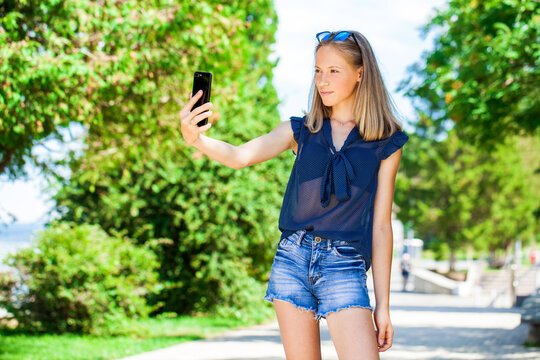 Happy beautiful girl taking pictures of herself on a mobile phone