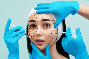 Close up portrait of a pretty young woman with surgical markings on her face. Hands of...