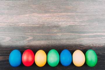 Colorful  easter eggs on wooden board background with space.