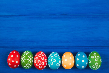 Colorful easter egg on blue color wood background with space.