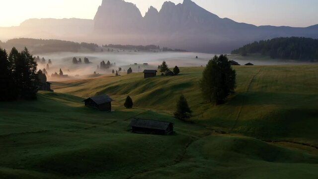 Drone passing above a man walking in Alpe di Siusi, Seiser Alm. Dolomites, South Tyrol, Italy. Sunrise.