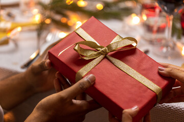 winter holidays and celebration concept - close up of hands holding christmas red gift box with...