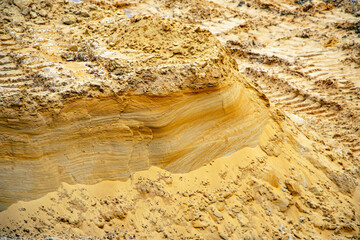 Textural sand, with  relief surface, multi-colored layers and different in size of granules, in outdoor sand career, after mining ore and sand for construction.