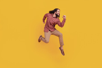 Photo of funky active energetic man jump run wear checkered shirt isolated on yellow color...