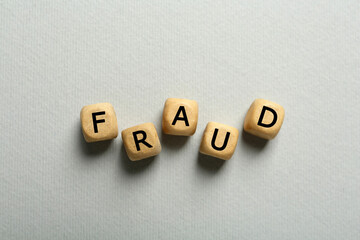 Word Fraud of wooden cubes with letters on light  grey background, flat lay