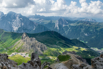 Fototapeta na wymiar Dolomites, 2017, panoramic view from the top of the Marmolada Passo Fedaia to the green valley, mountains in the distance and the cable car