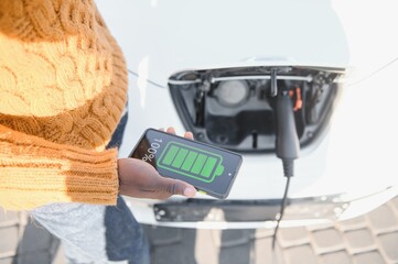 Smartphone app shows charging status of the electric car battery. Electro transport concept