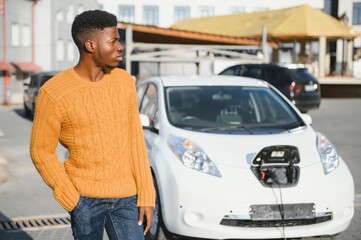 African American man charging his electric car.