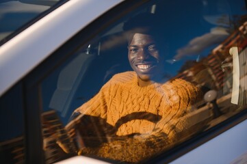 Handsome young African American man in his new high-tech electric vehicle while drinking. Self driving vehicle concept