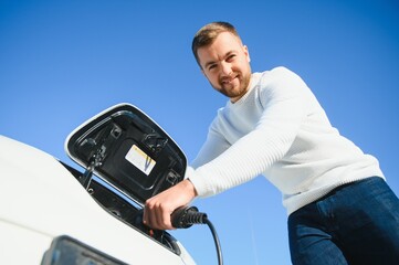 Man charges an electric car at the charging station
