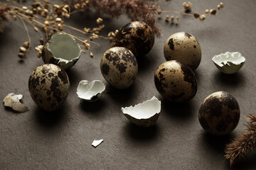 Small spotted eggs and eggshell pieces scattered on dark table surface easter concept