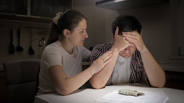 Young woman consoling her husband having financial problems. Concept of financial difficulties, poverty, bankruptcy, taxes and rent payment.