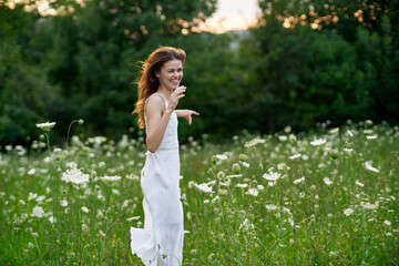 Fototapeta premium cheerful woman in a field with flowers in a white dress in nature