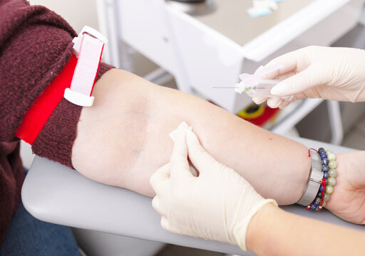 Nurse in white gloves is preparing to take the analysis from vein in woman