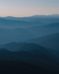 Fototapeta premium Mountain silhouette layers in the sunset light. Beautiful photography of the nature, blue layered background. Natural gradient.