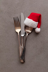 Silver knife fork and spoon with a Santa Claus red festive hat. Christmas meal background