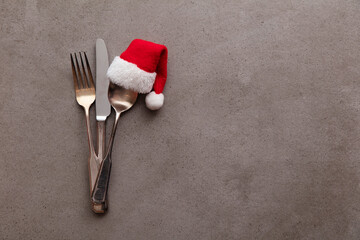 Silver knife fork and spoon with a Santa Claus red festive hat. Christmas meal background
