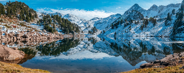 Reflection of the snowy mountains in the beautiful Baciver lake in the Pyrenees mountains of Val...