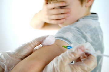 close-up syringe in hands of doctor, nurse in gloves makes injection to 8 years old, medical concept, vaccination against coronavirus covid-19 virus, intramuscular vitamins, insulin