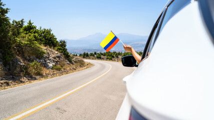Woman holding Colombia flag from the open car window driving along the serpentine road in the...