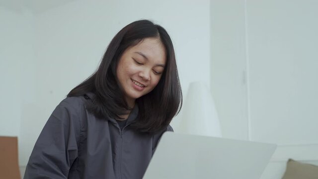 4k, Portrait, a cute Asian teenage girl. wearing gray shirt studying online with notebook computer in bed in the bedroom happily