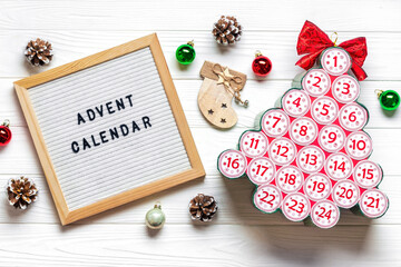 Felt board, advent calendar in shape of Christmas tree with numbers and ribbon instead of star on white wooden table Xmas advent calendar concept Top view Flat lay Holiday card