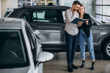 Fototapeta na wymiar Young couple choosing a car in a car show room