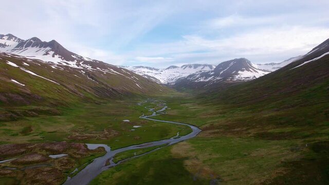 Incredibly beautiful aerial of Icelandic mountains and green valley with river below. Majestic scenery. 