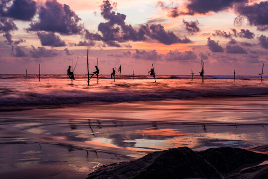 Unrecognizable fishermen on poles in sea