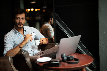 Handsome businessman working on laptop and sitting in cafe. Young man having video call