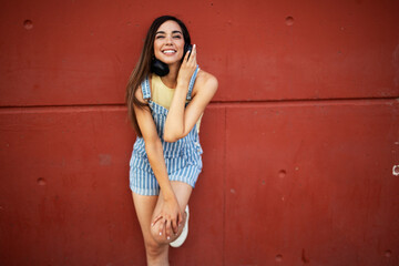 Young happy woman listening to music outdoors. Positive hipster girl with headphones enjoying in sunny day..